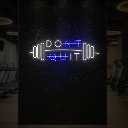 'Don’t Quit (with Barbell)' neon sign glowing in deep blue against a styled interior wall.