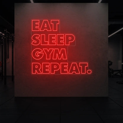 'Eat Sleep Gym Repeat' neon sign glowing in red against a styled interior wall.