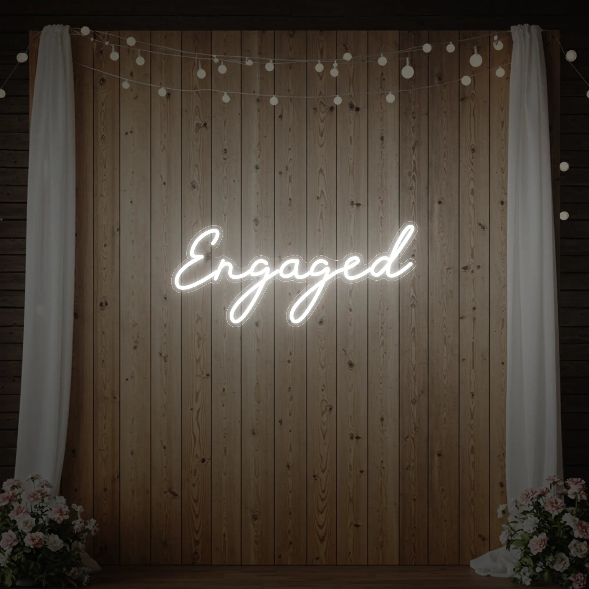 Photo of the 'Engaged' neon sign glowing in cool white against a styled interior wall.