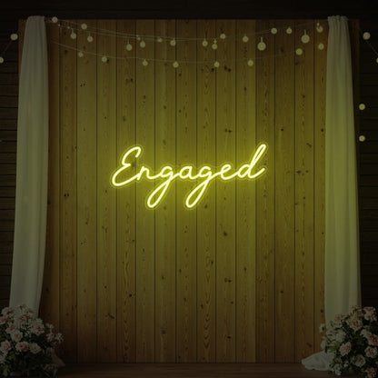 Photo of the 'Engaged' neon sign glowing in lemon yellow against a styled interior wall.