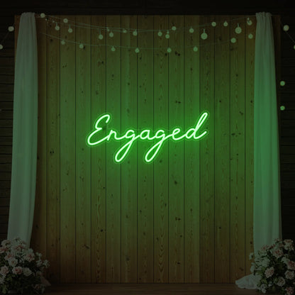 Photo of the 'Engaged' neon sign glowing in green against a styled interior wall.
