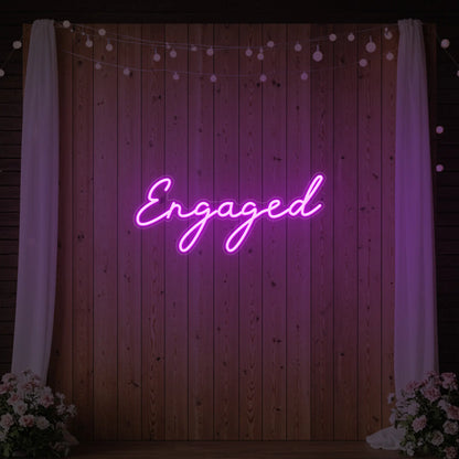 Photo of the 'Engaged' neon sign glowing in deep pink against a styled interior wall.