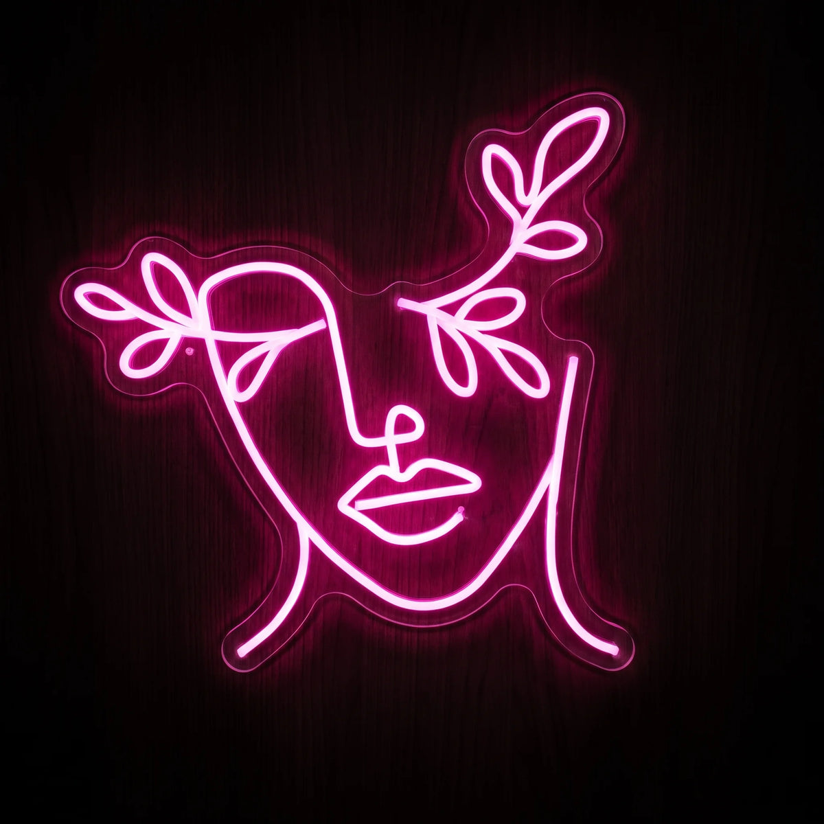 Pink floral line art face LED neon sign with abstract facial outline and leafy accents on clear acrylic backing.