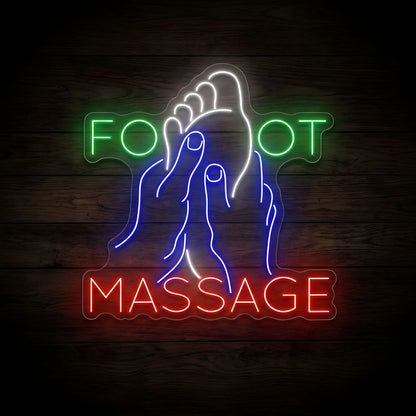 Foot Massage Reflexology LED Neon Sign featuring a white foot being massaged by blue hands, green FOOT lettering, and red MASSAGE lettering on clear acrylic backing against a dark wooden wall.