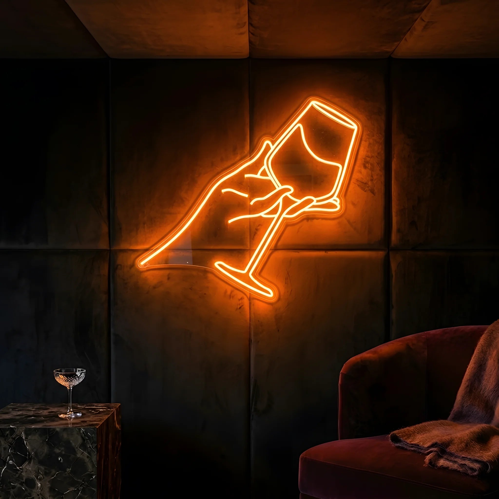 Photo of the 'Hand Holding Wine Glass' neon sign glowing in golden yellow against a styled interior wall.