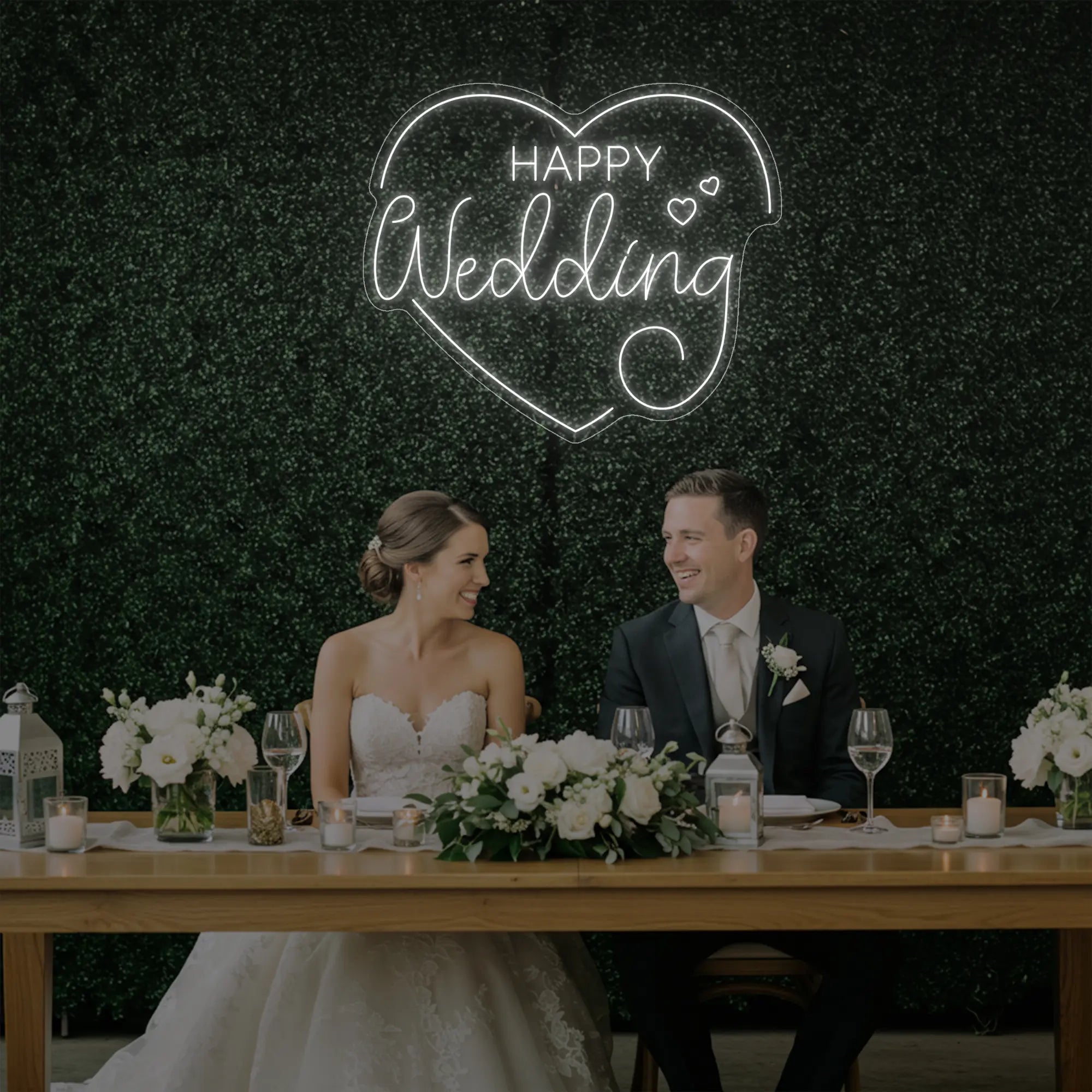 Photo of the 'Happy Wedding' neon sign glowing in cool white against a styled interior wall.