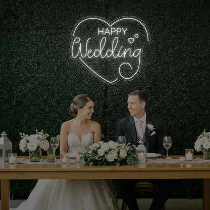 Photo of the 'Happy Wedding' neon sign glowing in cool white against a styled interior wall.