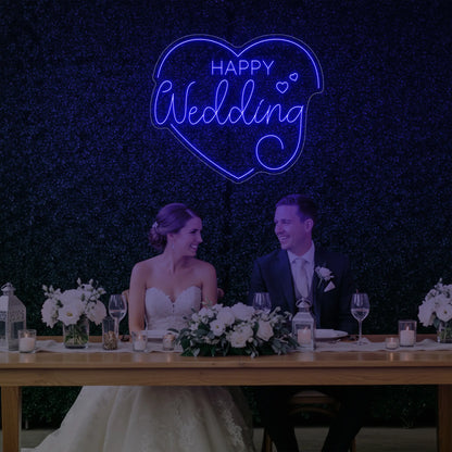 Photo of the 'Happy Wedding' neon sign glowing in deep blue against a styled interior wall.