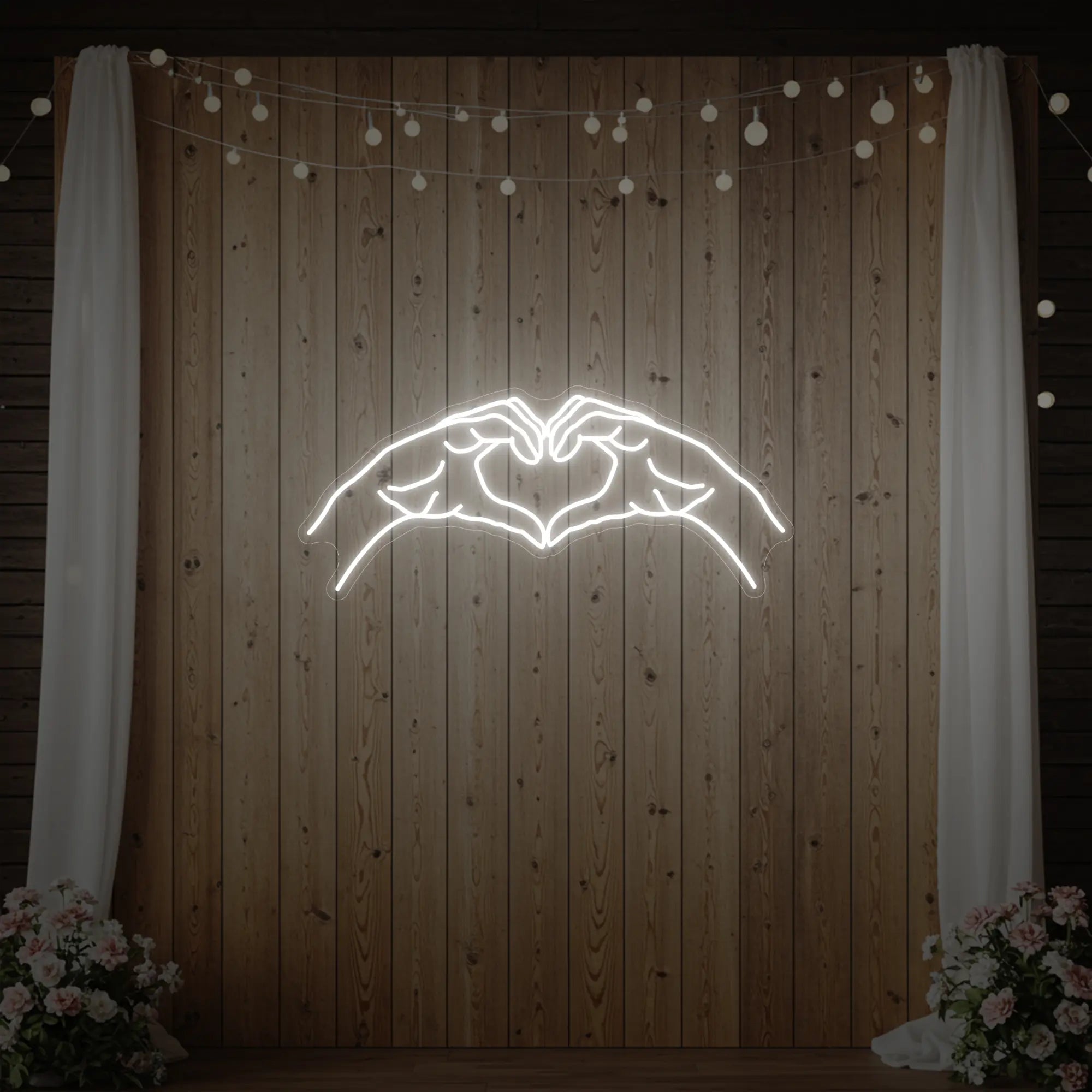 Photo of the 'Heart Hands' neon sign glowing in cool white against a styled interior wall.