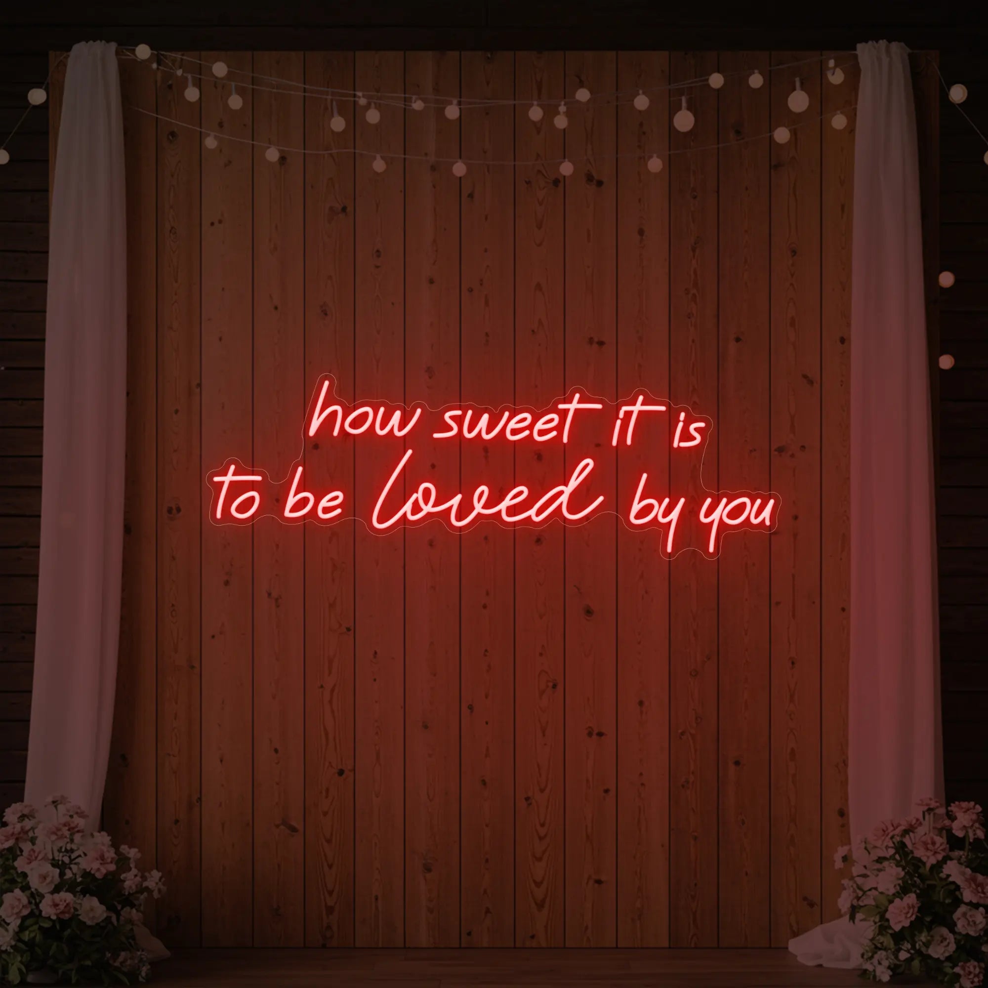 Photo of the 'How Sweet It Is To Be Loved By You' neon sign glowing in red against a styled interior wall.