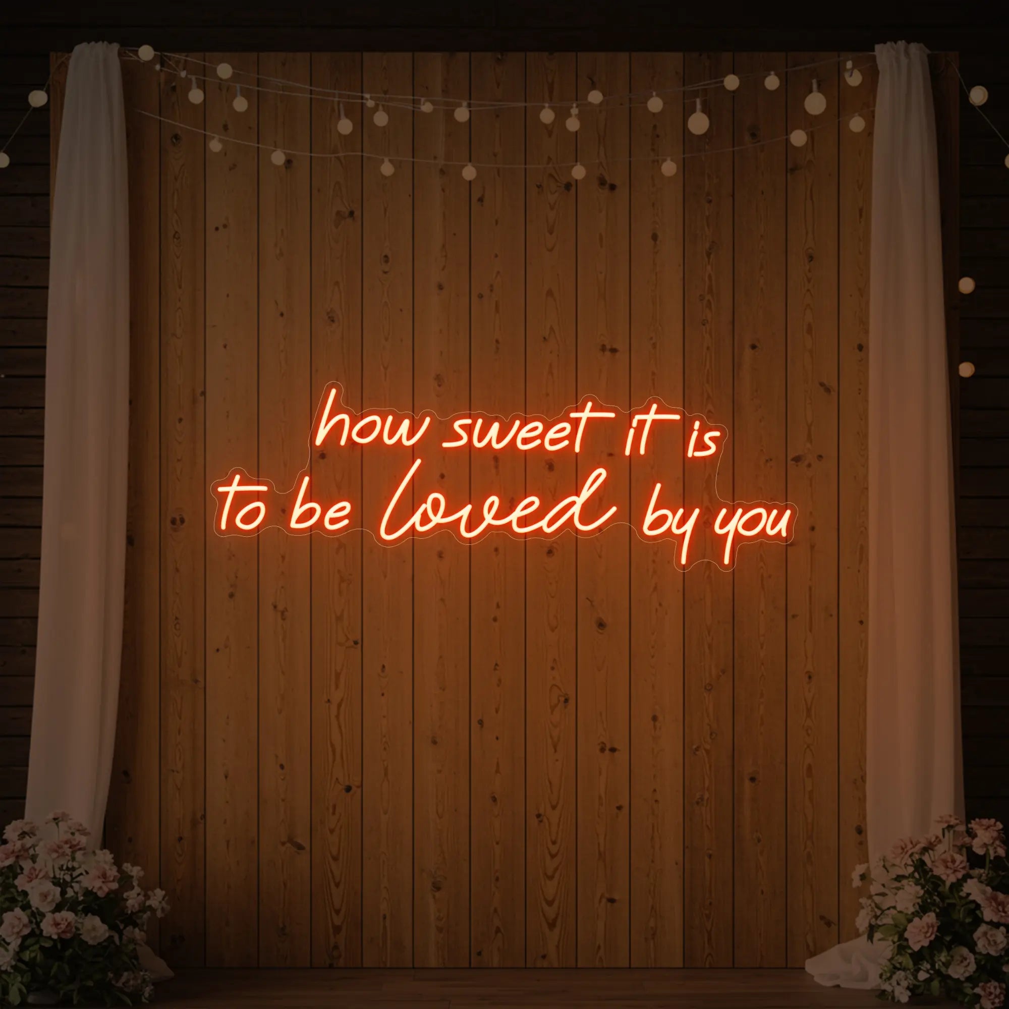 Photo of the 'How Sweet It Is To Be Loved By You' neon sign glowing in golden yellow against a styled interior wall.
