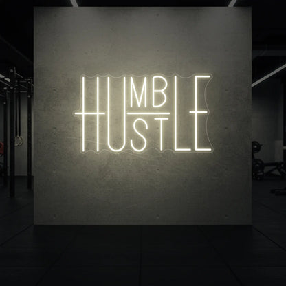 'Humble Hustle' neon sign glowing in warm white against a styled interior wall.