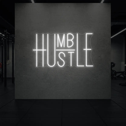  'Humble Hustle' neon sign glowing in cool white against a styled interior wall.