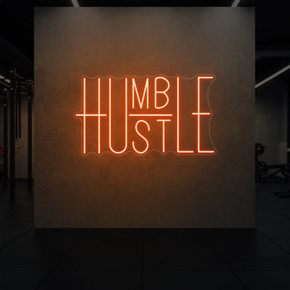 'Humble Hustle' neon sign glowing in golden yellow against a styled interior wall.