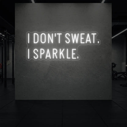 'I DON'T SWEAT. I SPARKLE.' neon sign glowing in cool white against a styled interior wall.