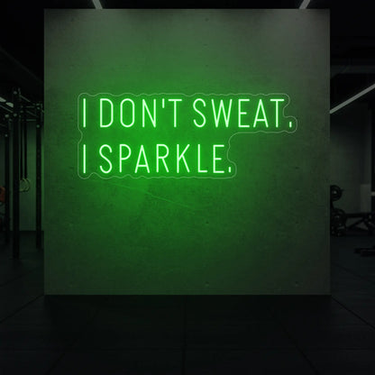  'I DON'T SWEAT. I SPARKLE.' neon sign glowing in green against a styled interior wall.