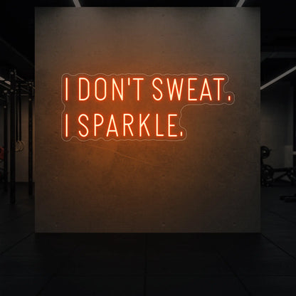  'I DON'T SWEAT. I SPARKLE.' neon sign glowing in golden yellow against a styled interior wall.