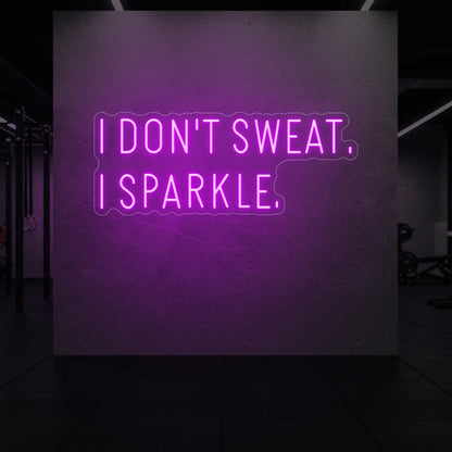 'I DON'T SWEAT. I SPARKLE.' neon sign glowing in deep pink against a styled interior wall.