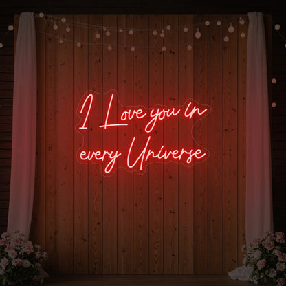 Photo of the 'I Love You In Every Universe' neon sign glowing in red against a styled interior wall.