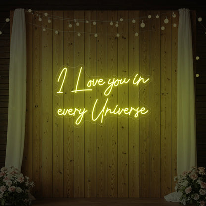 Photo of the 'I Love You In Every Universe' neon sign glowing in lemon yellow against a styled interior wall.