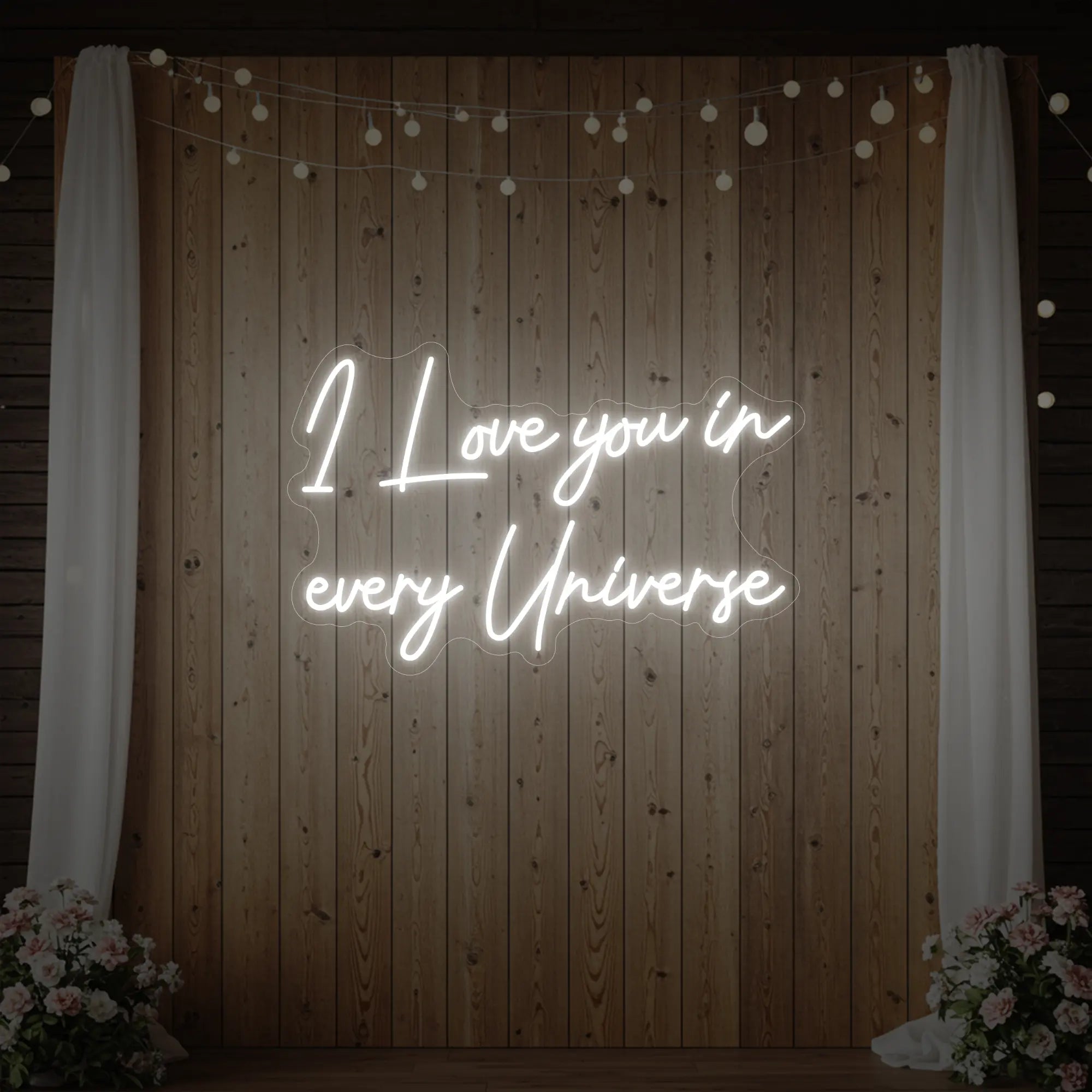 Photo of the 'I Love You In Every Universe' neon sign glowing in cool white against a styled interior wall.