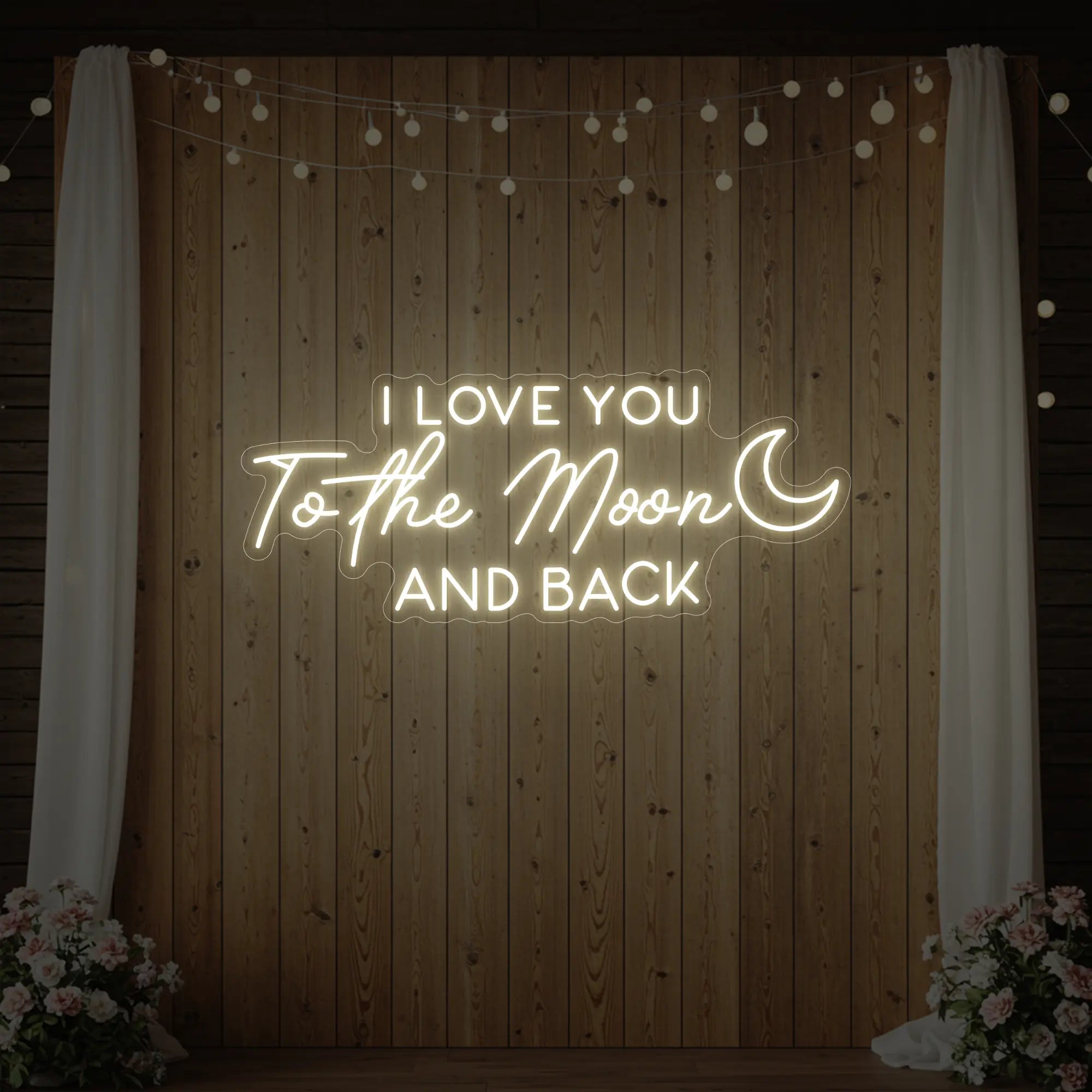Photo of the 'I Love You To The Moon And Back' neon sign glowing in warm white against a styled interior wall.