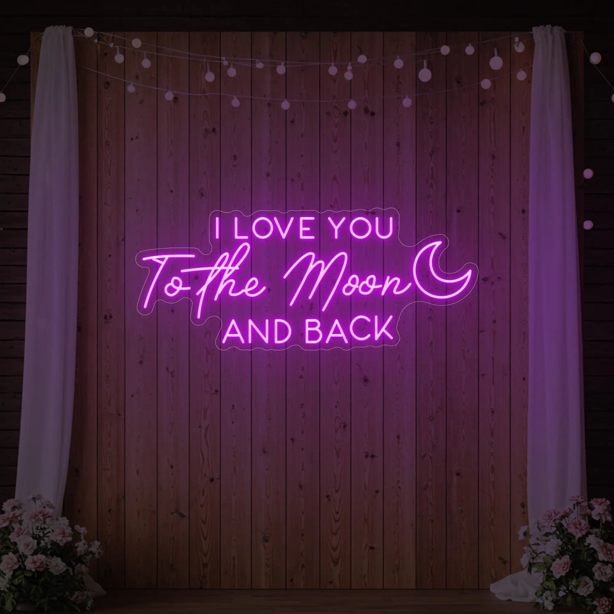 Photo of the 'I Love You To The Moon And Back' neon sign glowing in deep pink against a styled interior wall.