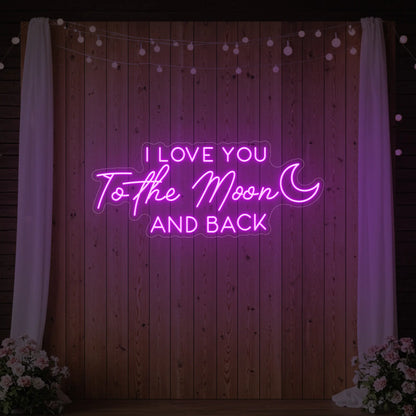 Photo of the 'I Love You To The Moon And Back' neon sign glowing in deep pink against a styled interior wall.