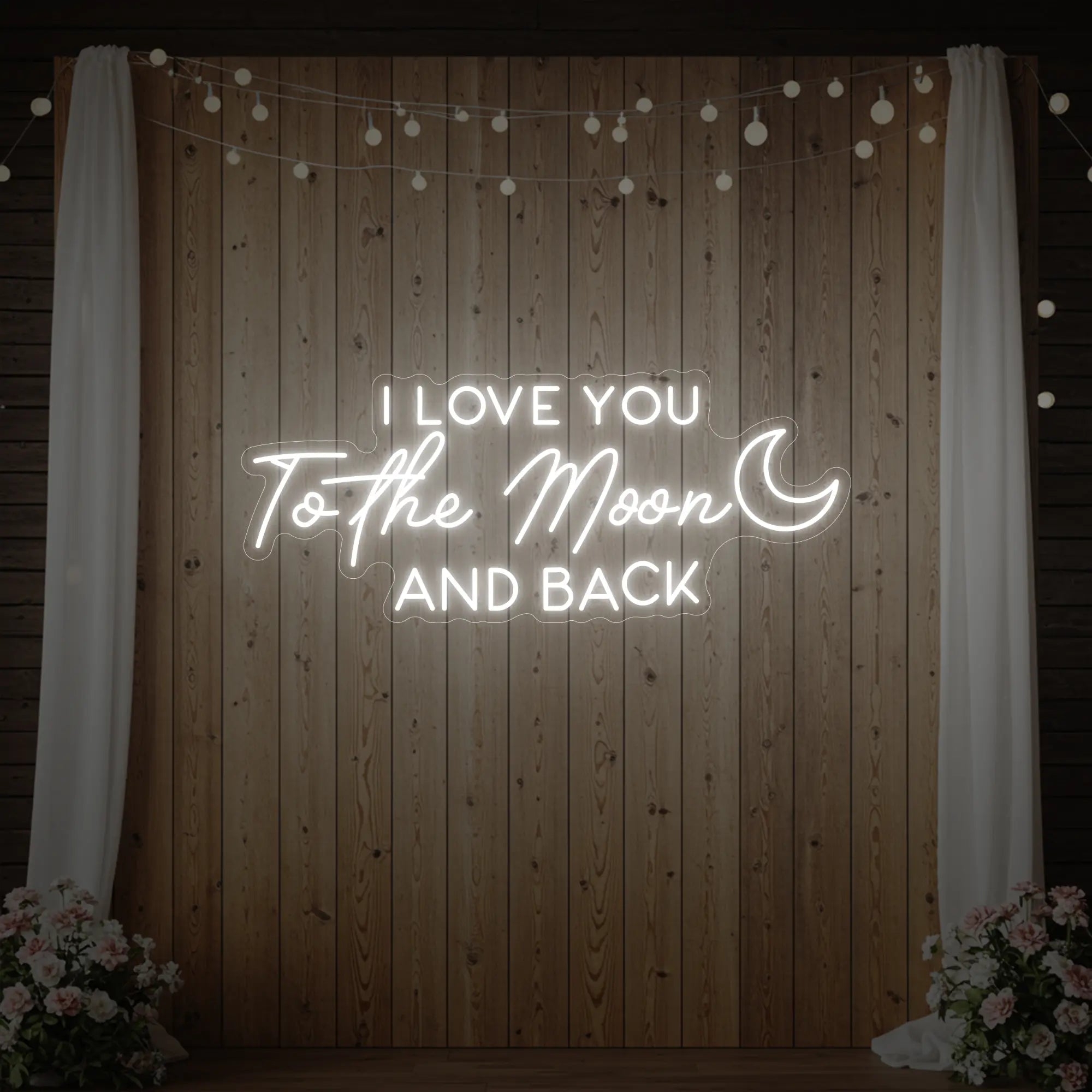 Photo of the 'I Love You To The Moon And Back' neon sign glowing in cool white against a styled interior wall.