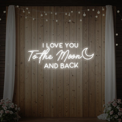 Photo of the 'I Love You To The Moon And Back' neon sign glowing in cool white against a styled interior wall.