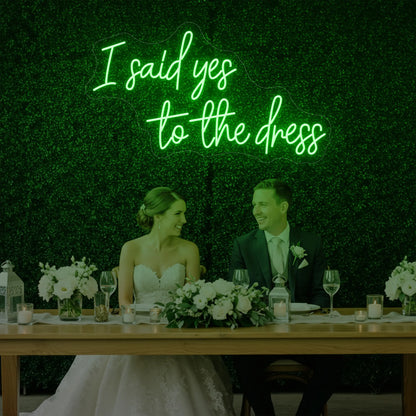 Photo of the 'I Said Yes To The Dress' neon sign glowing in green against a styled interior wall.