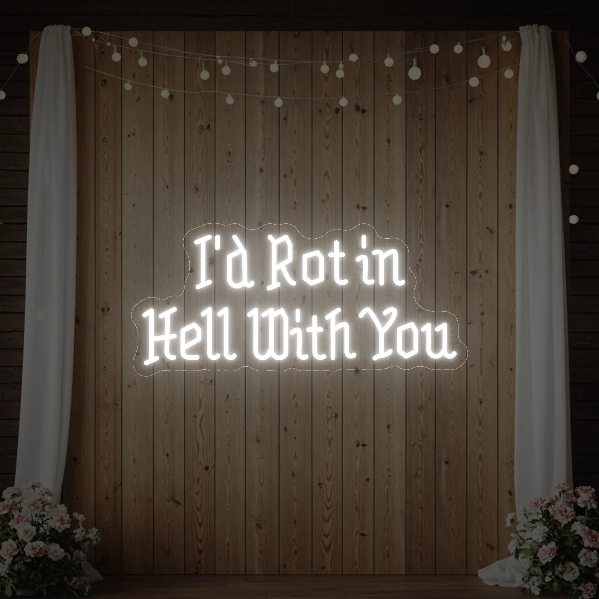 Photo of the 'I’d Rot in Hell With You' neon sign glowing in cool white against a styled interior wall.