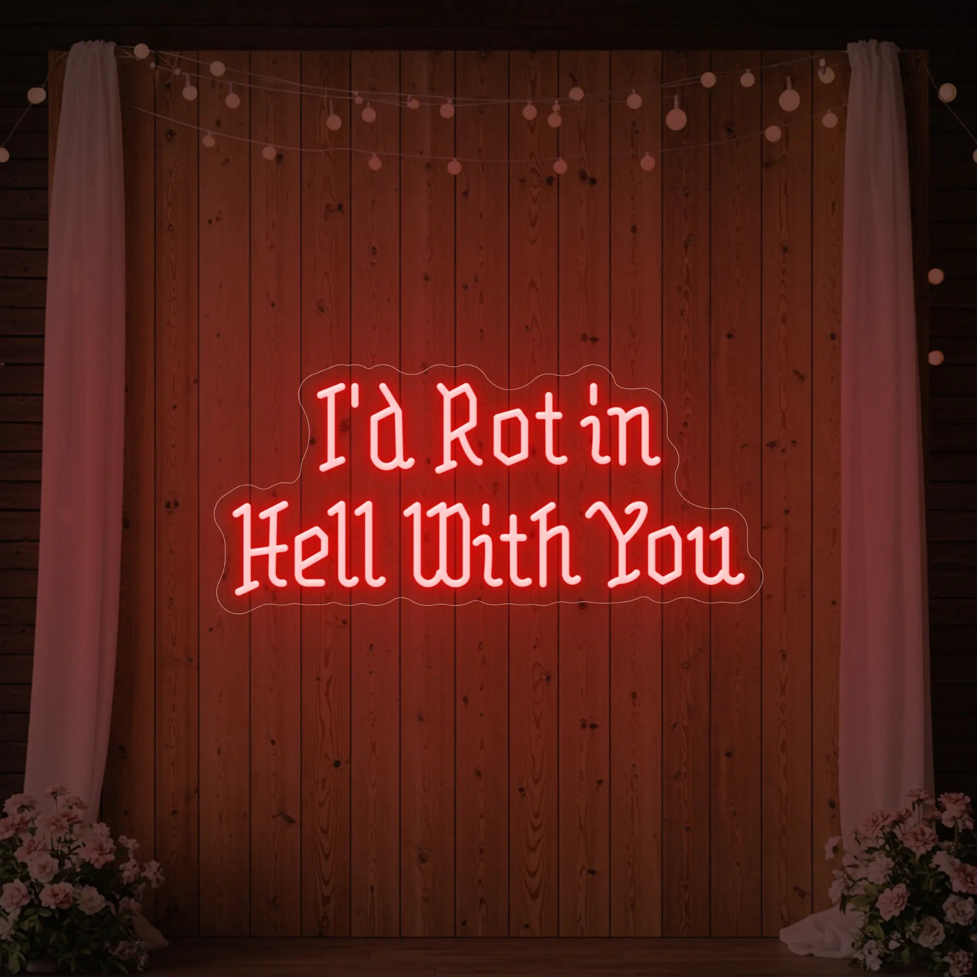 Photo of the 'I’d Rot in Hell With You' neon sign glowing in red against a styled interior wall.