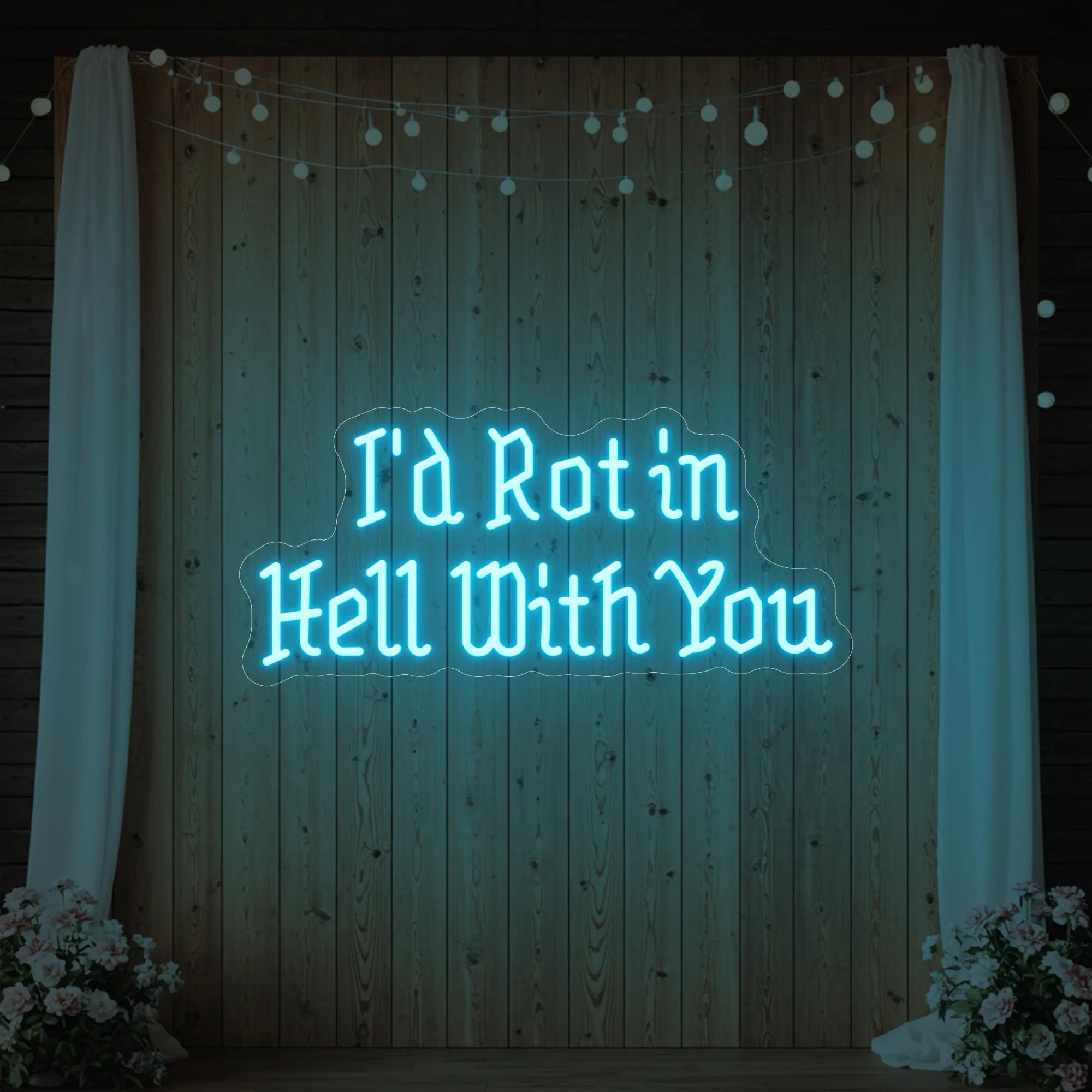 Photo of the 'I’d Rot in Hell With You' neon sign glowing in ice blue against a styled interior wall.