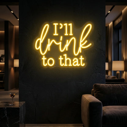 Photo of the 'I’ll Drink to That' neon sign glowing in lemon yellow against a styled interior wall.