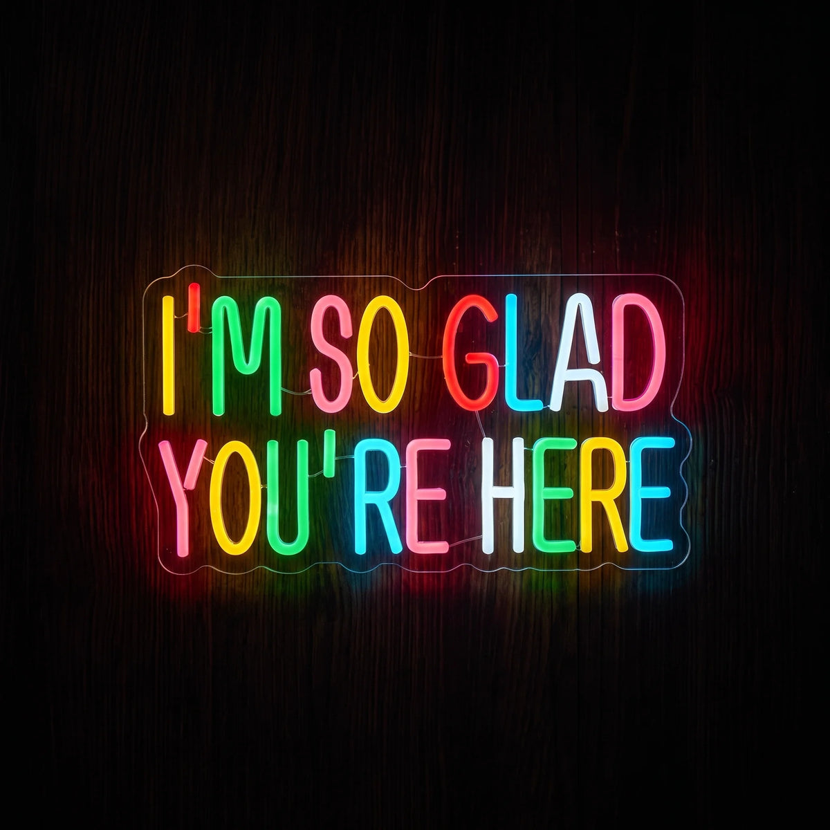 I'm So Glad You're Here LED Neon Sign with colorful multicolor lettering on clear acrylic backing.