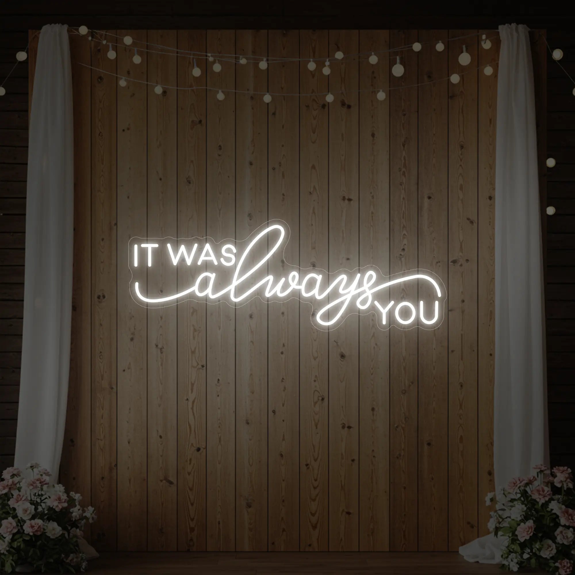 Photo of the 'It Was Always You' neon sign glowing in cool white against a styled interior wall.