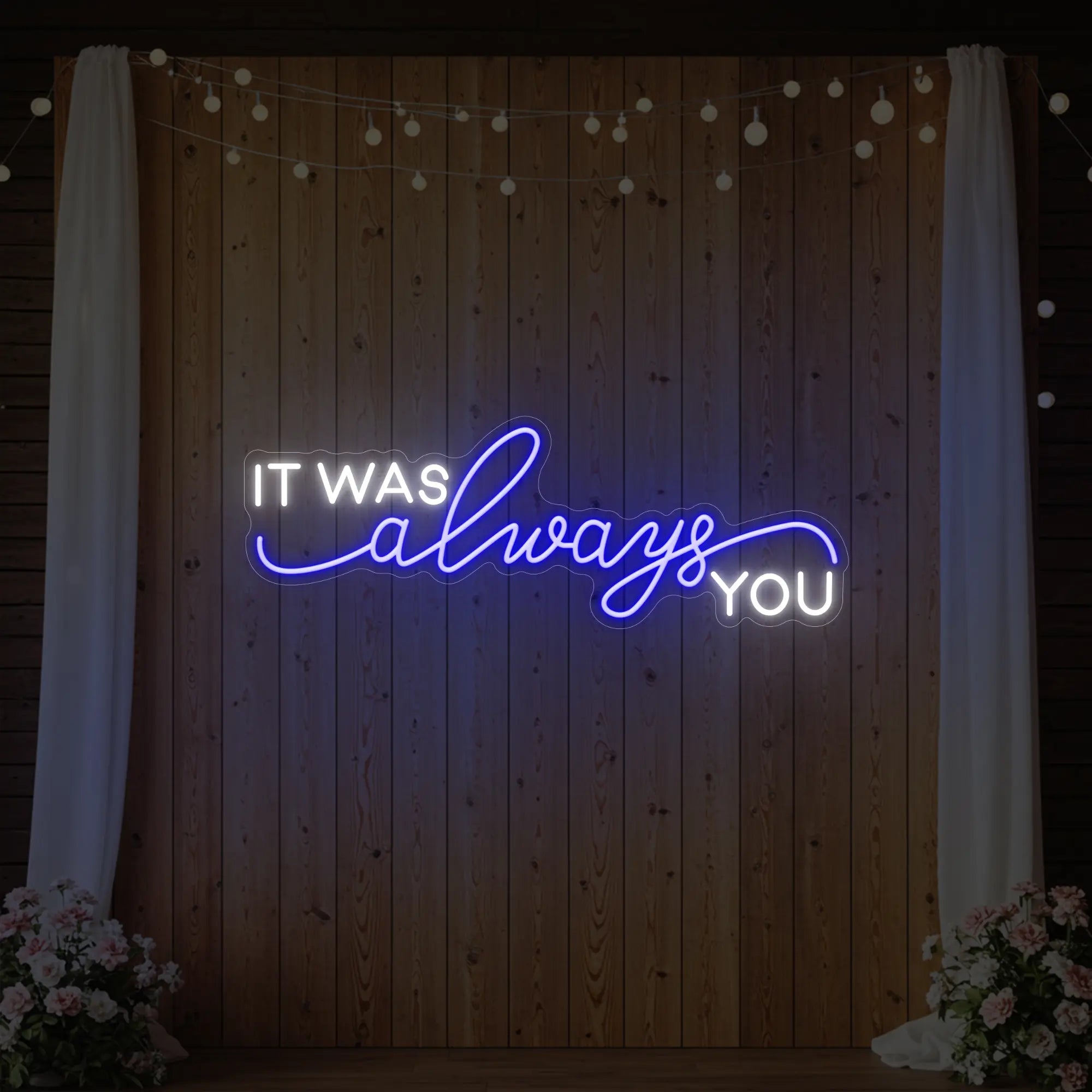 Photo of the 'It Was Always You' neon sign glowing in deep blue against a styled interior wall.