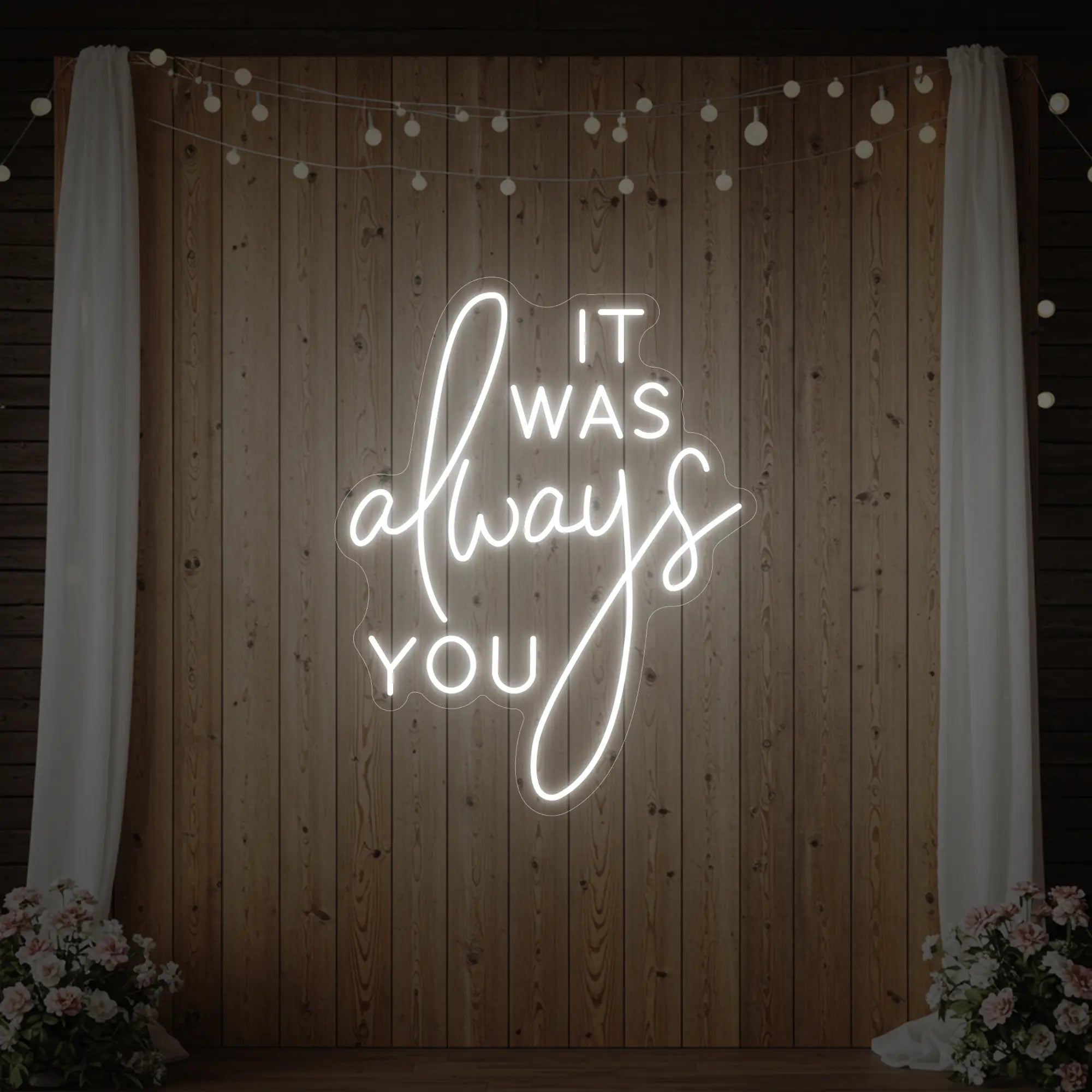 Photo of the 'It Was Always You' neon sign glowing in cool white against a styled interior wall.