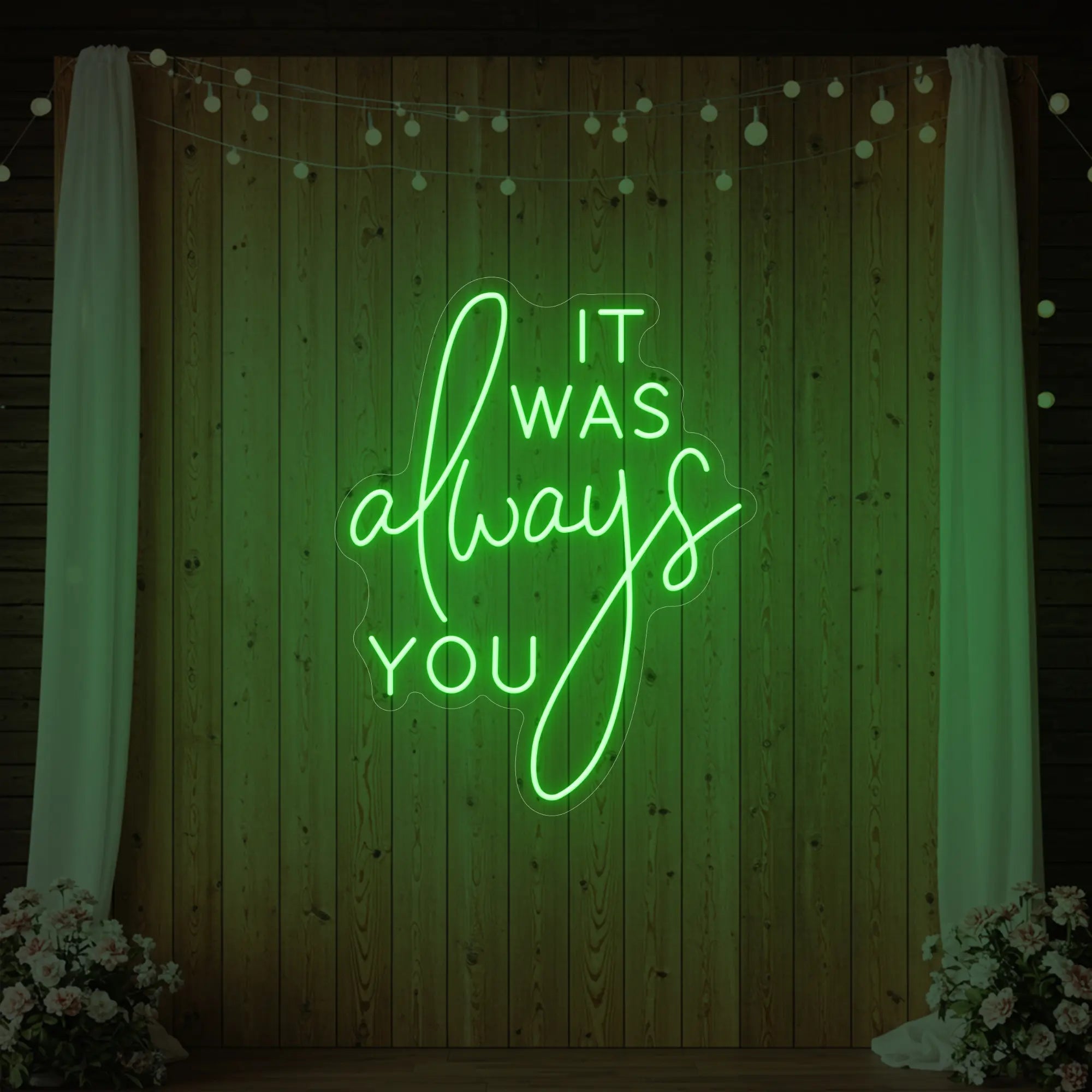 Photo of the 'It Was Always You' neon sign glowing in green against a styled interior wall.