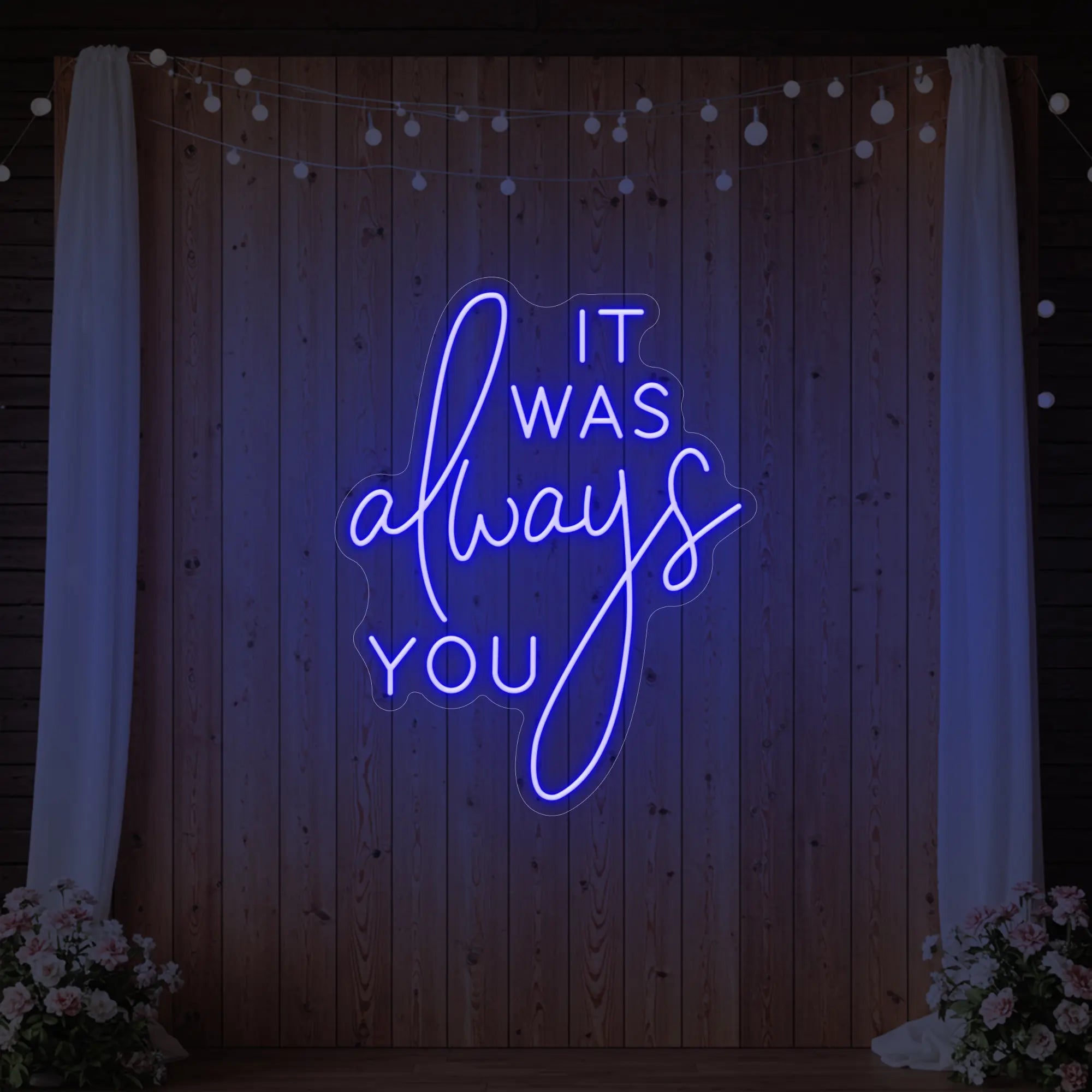 Photo of the 'It Was Always You' neon sign glowing in deep blue against a styled interior wall.