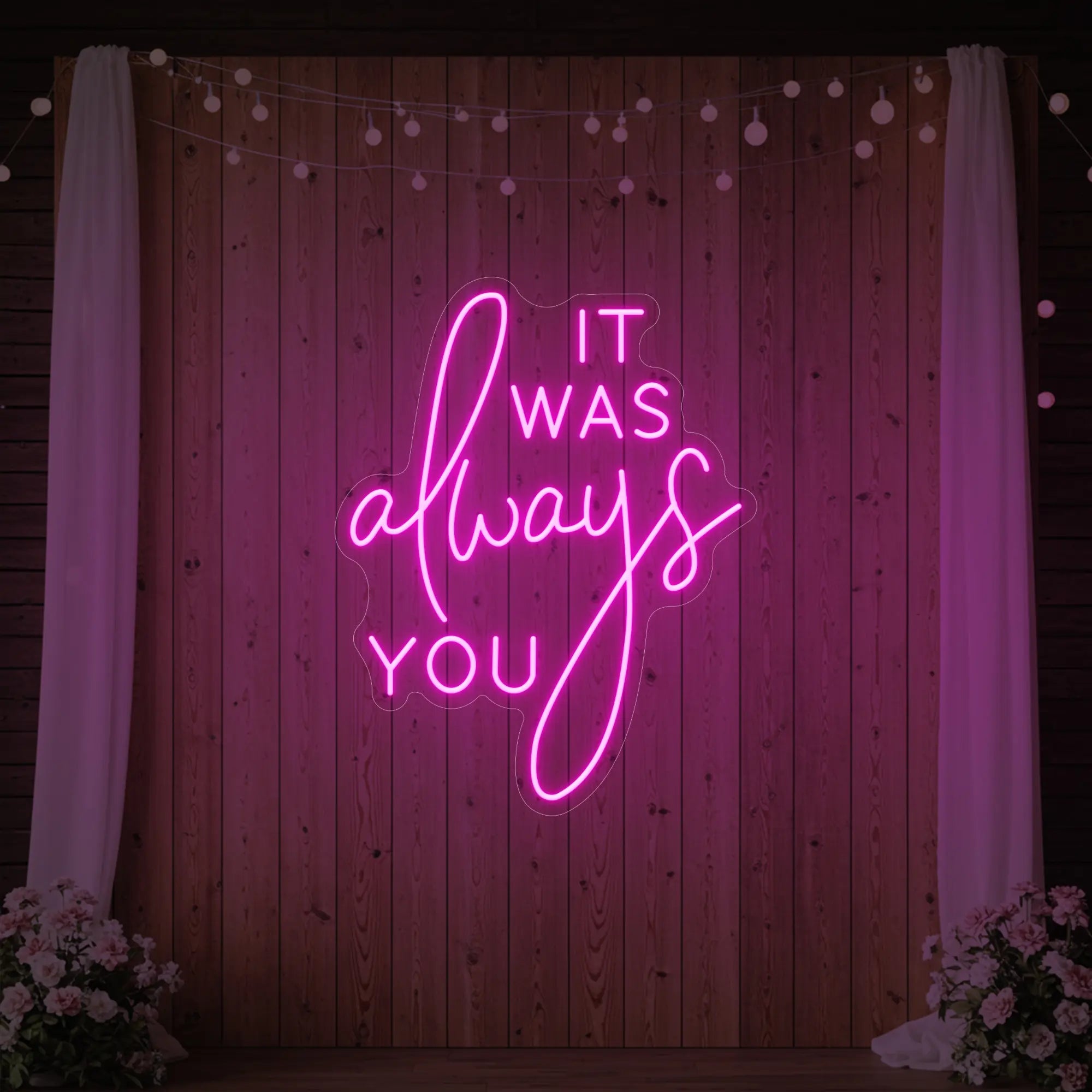 Photo of the 'It Was Always You' neon sign glowing in light pink against a styled interior wall.