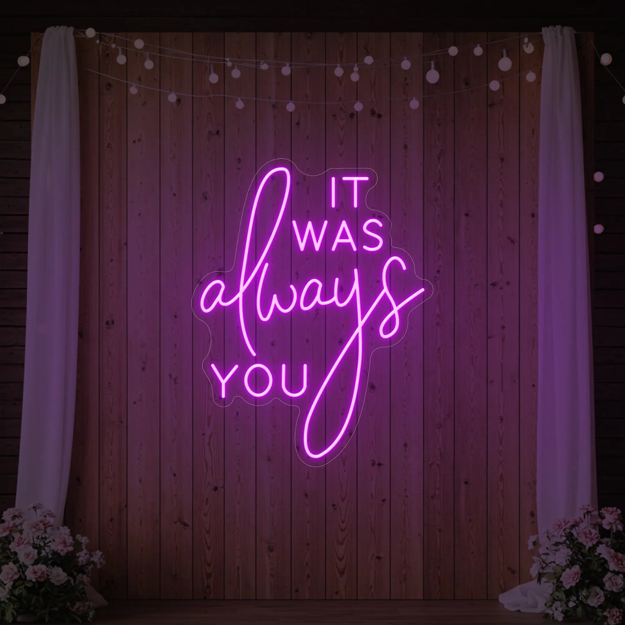 Photo of the 'It Was Always You' neon sign glowing in deep pink against a styled interior wall.