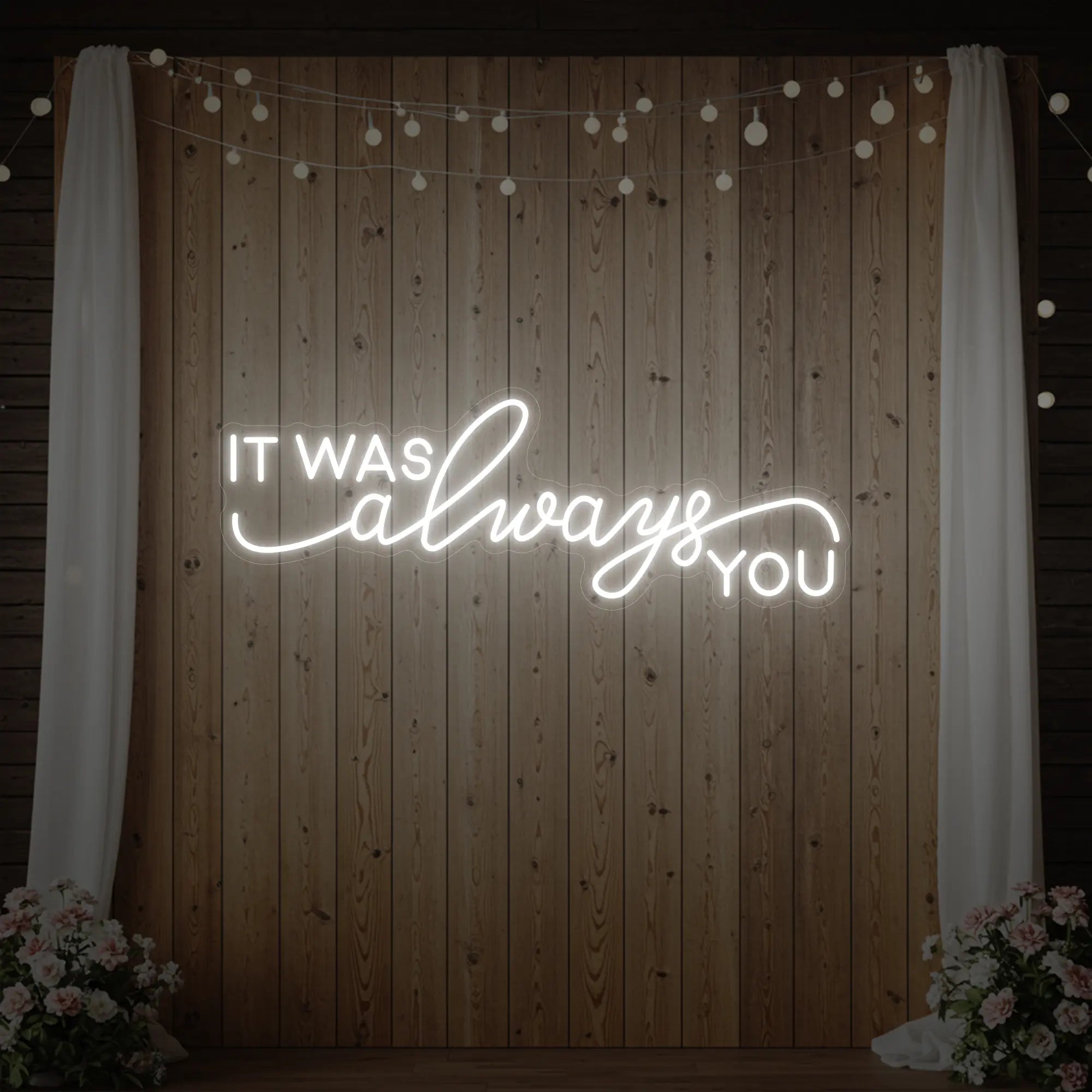 Photo of the 'It Was Always You' neon sign glowing in cool white against a styled interior wall.