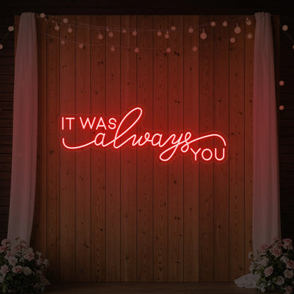 Photo of the 'It Was Always You' neon sign glowing in red against a styled interior wall.