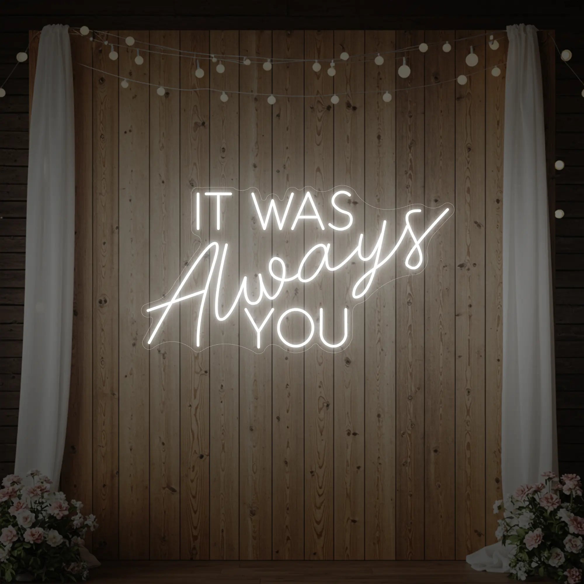 Photo of the 'It Was Always You' neon sign glowing in cool white against a styled interior wall.