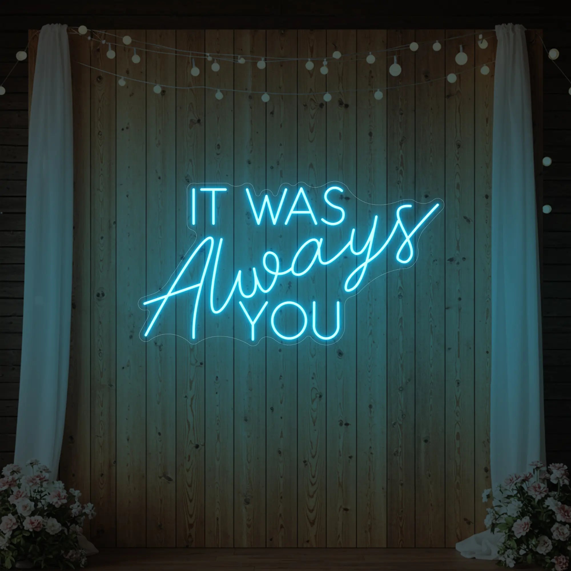 Photo of the 'It Was Always You' neon sign glowing in ice blue against a styled interior wall.