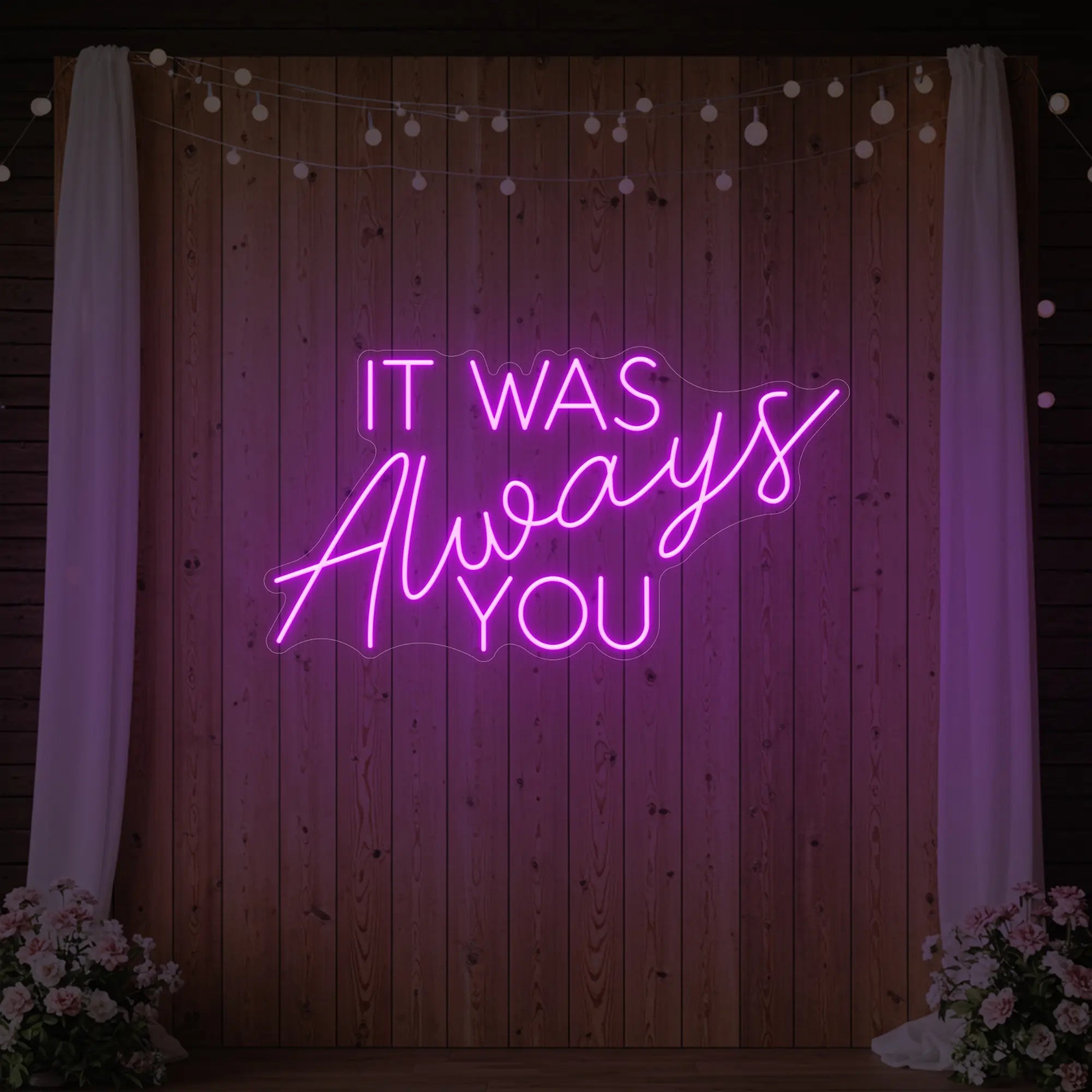 Photo of the 'It Was Always You' neon sign glowing in deep pink against a styled interior wall.