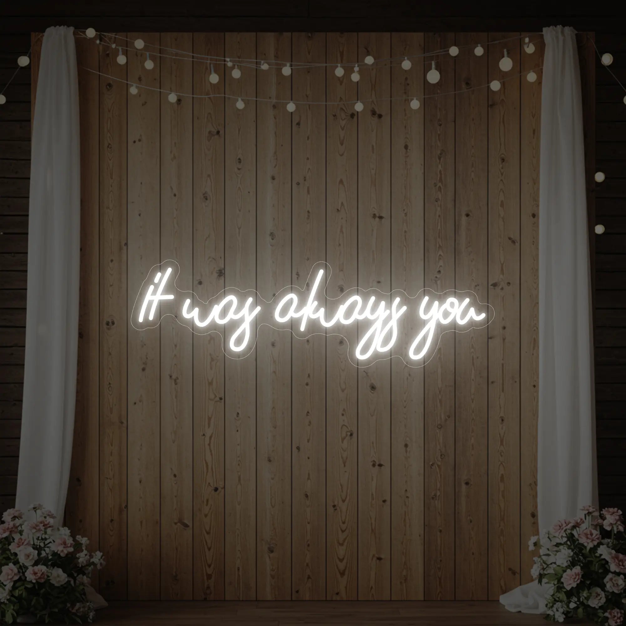 Photo of the 'It Was Always You' neon sign glowing in cool white against a styled interior wall.