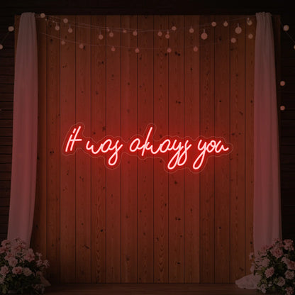 Photo of the 'It Was Always You' neon sign glowing in red against a styled interior wall.